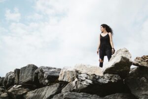 Woman standing strong on a rocky ledge, open sky in the background