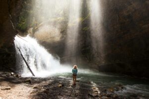 Woman standing in a cove or cave with light shining down from above