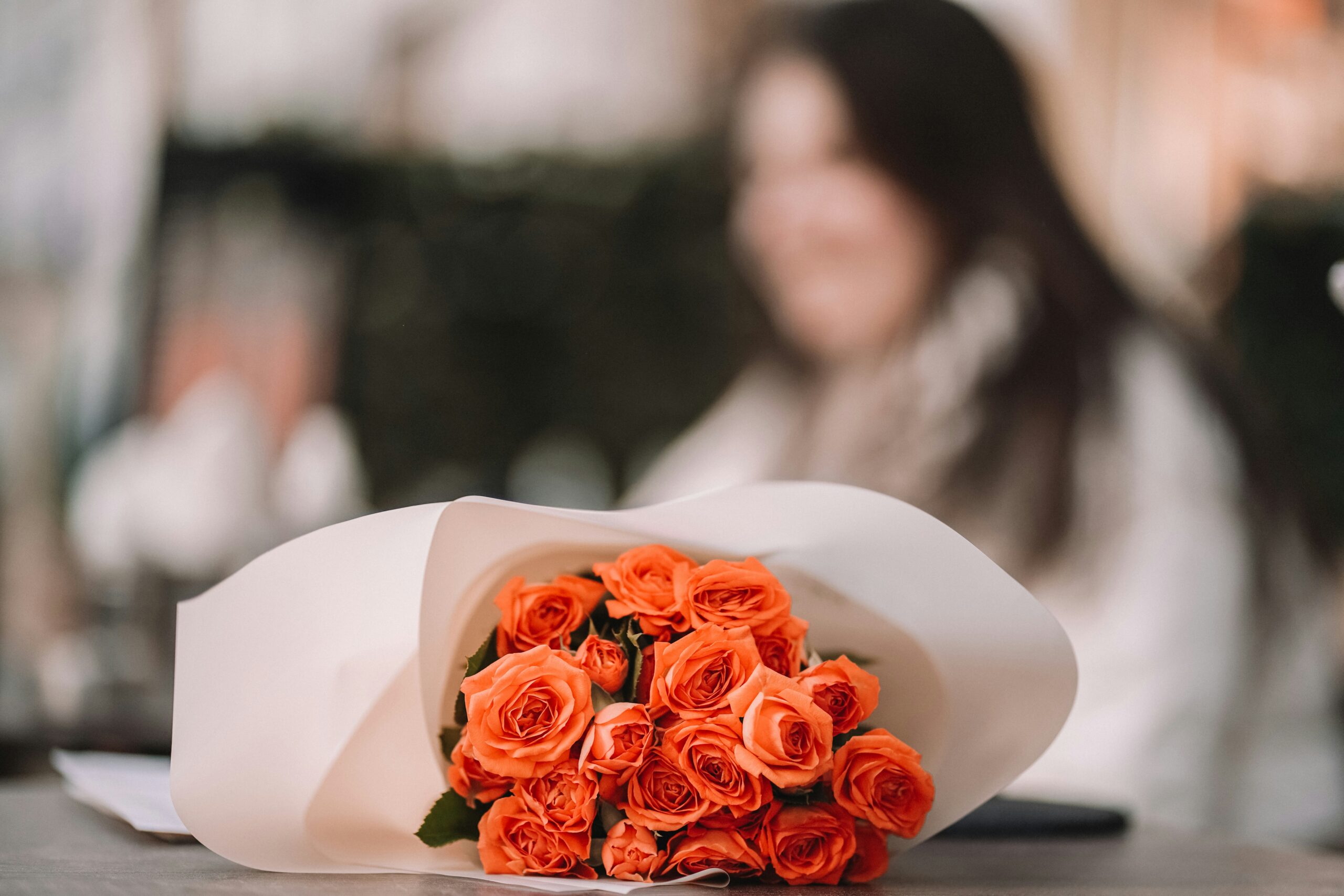 Coral Roses in the foreground, laying on a table.