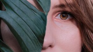 Woman hiding half her face with a leaf but still watching