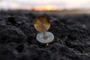 A brass compass on a rocky coast, needle pulled off true — guilt after setting boundaries is a compass someone re-magnetized.