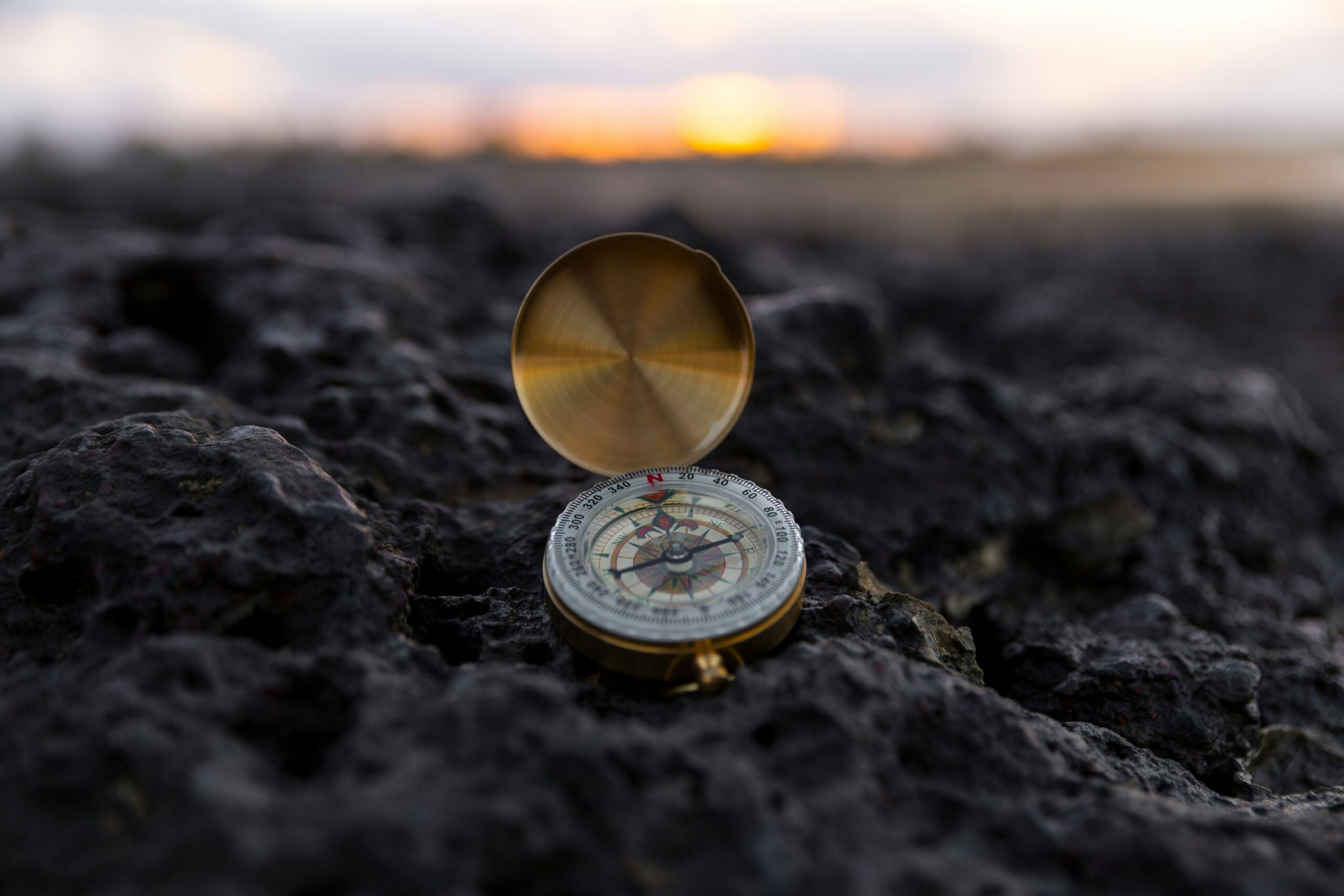A brass compass on a rocky coast, needle pulled off true — guilt after setting boundaries is a compass someone re-magnetized.