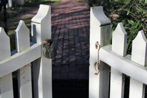 A white picket gate standing open, latch and handle clearly visible