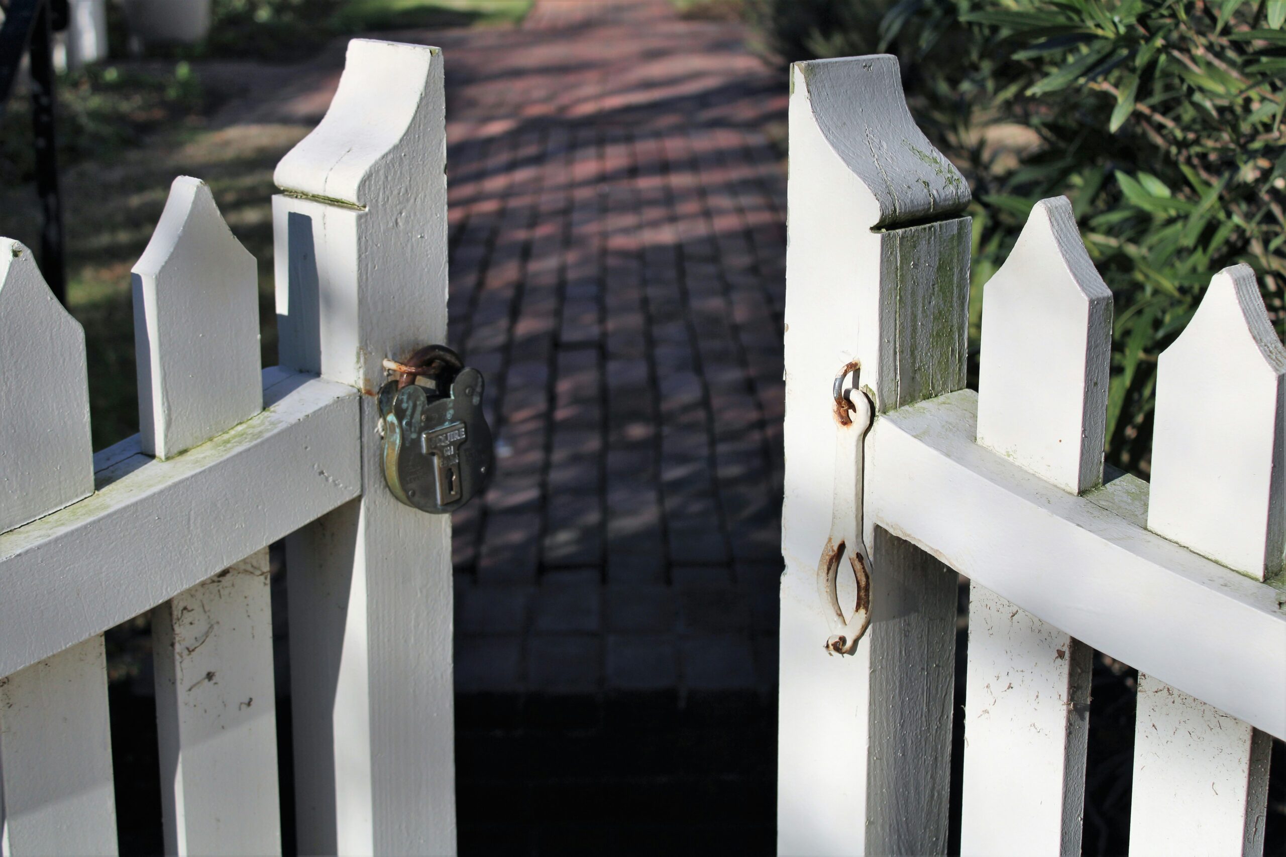 A white picket gate standing open, latch and handle clearly visible