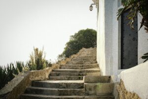 Stone steps climbing past a closed wooden door beside a white wall